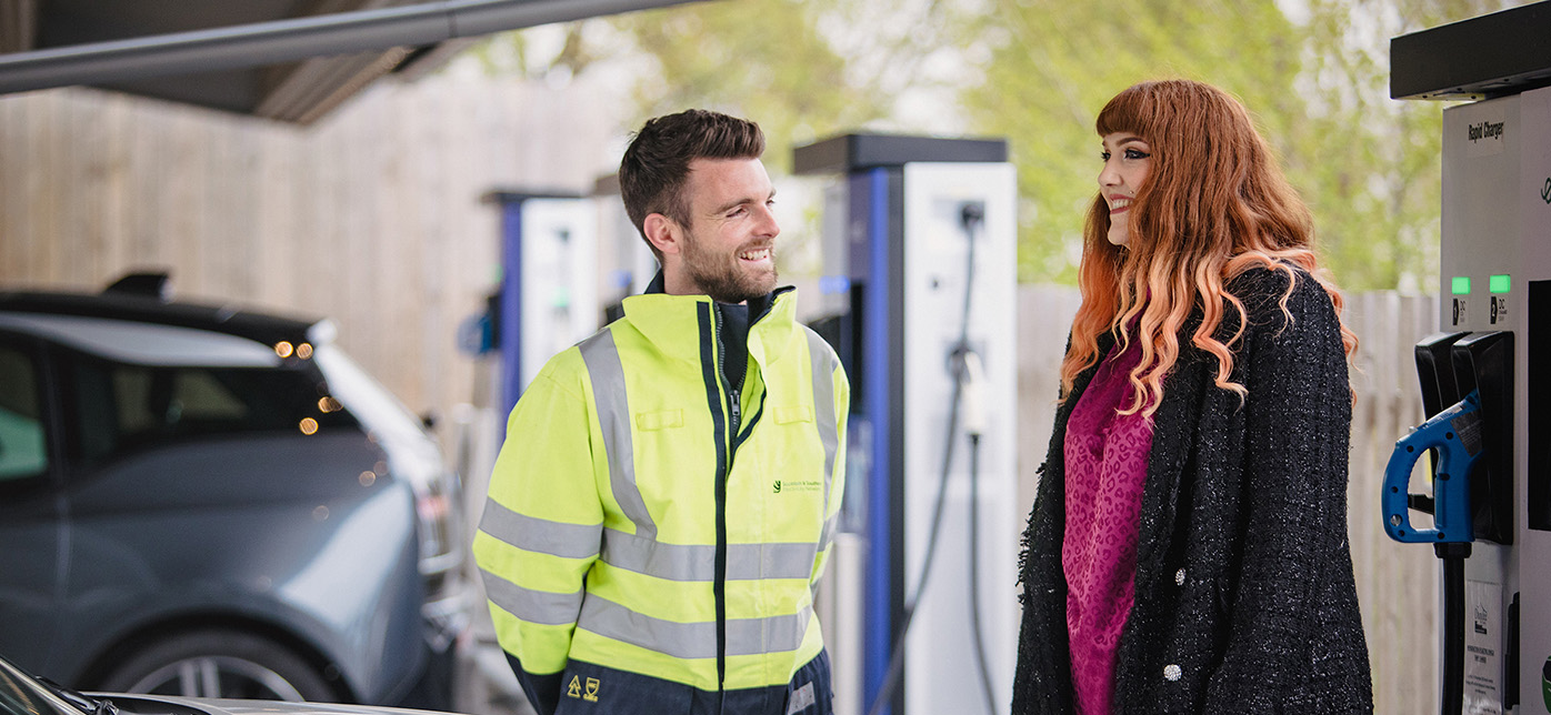 Engineer speaking with customer next to electric vehicle