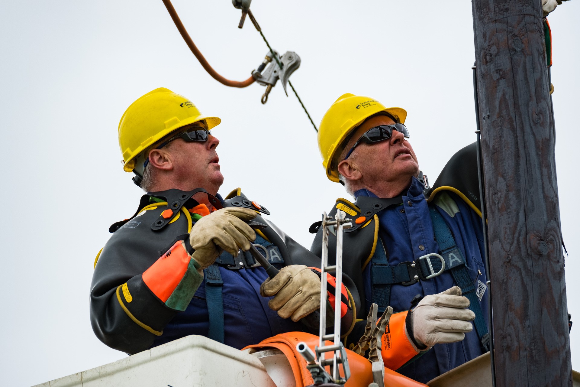 Two engineers in high vis and hard hats working on overhead line