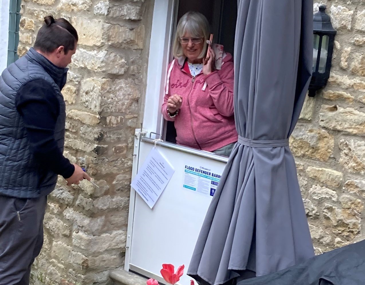 Female resident stands at front door with flood barrier