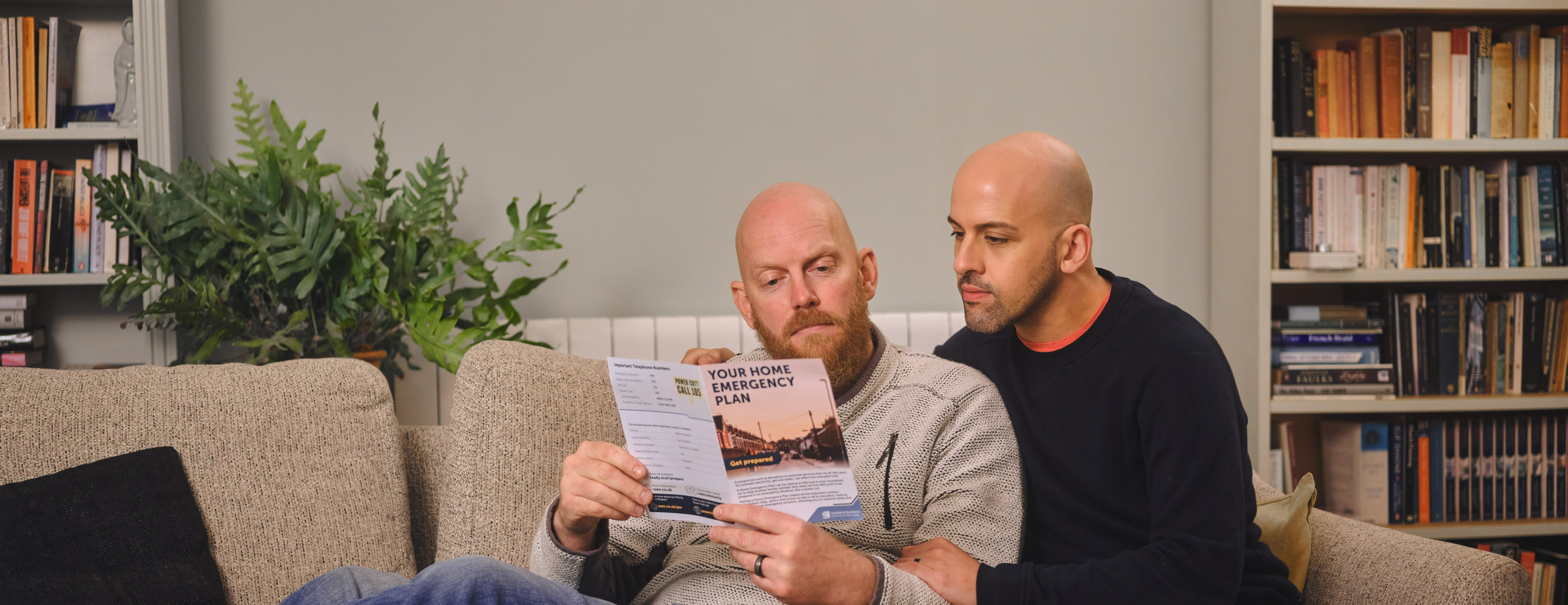 Couple on the sofa, reading SSEN leaflet.