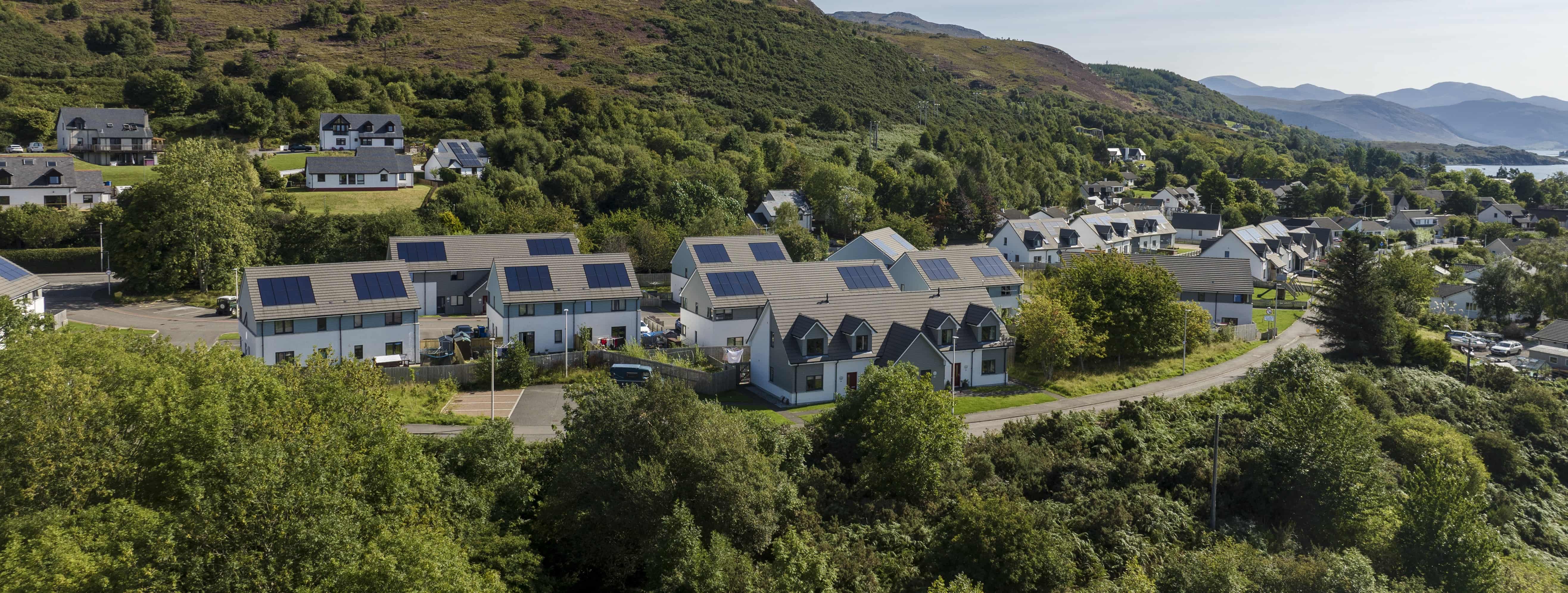 Photo shot of houses, surrounded by lots of green scenery.
